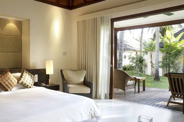 Schlafzimmer im Coco de Mer Hotel mit einem großen Bett, Kissen und Lampen neben dem Bett.