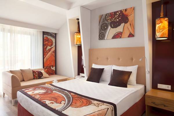 Hotelzimmer im Side Orange Palace mit großem Bett, Sofa und Kunstwerken an der Wand.