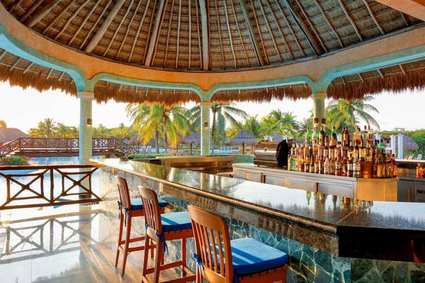 Bar im Grand Palladium White Sand Resort & Spa mit vielen Flaschen und Palmen im Hintergrund