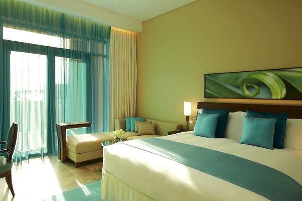 Hotelzimmer im Sofitel Dubai The Palm mit großem Bett, Sofa und Fenstern.