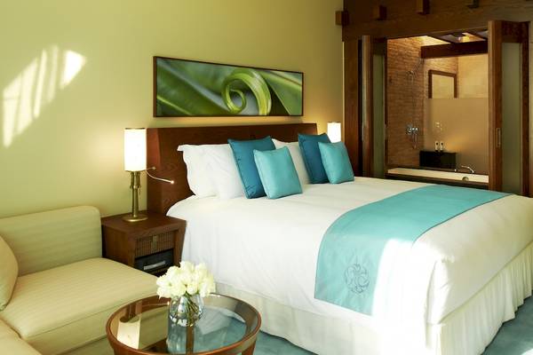 Schlafzimmer im Sofitel Dubai The Palm mit blauen Kissen und einem großen Bett.