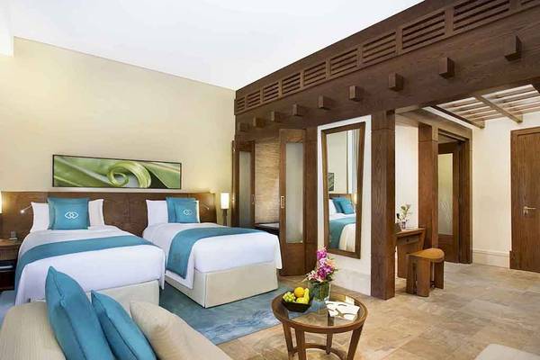 Doppelbett-Zimmer im Sofitel Dubai The Palm mit zwei Betten, einem Tisch und einem Wohnzimmerbereich.