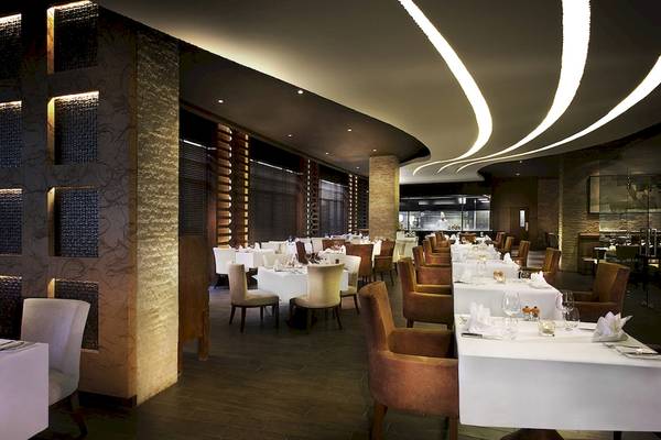 Innenansicht des Restaurants im Sofitel Dubai The Palm mit gedeckten Tischen und eleganter Beleuchtung.
