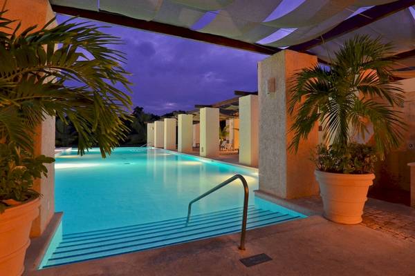 Poolbereich des Grand Palladium White Sand Resorts und Spa bei Nacht mit beleuchtetem Schwimmbecken und Pflanzen.