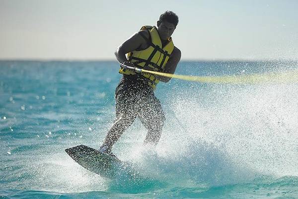 Ein Mann macht Wasserski im Ozean, gezogen von einem Boot, im Trou aux Biches Beachcomber Golf Resort & Spa.
