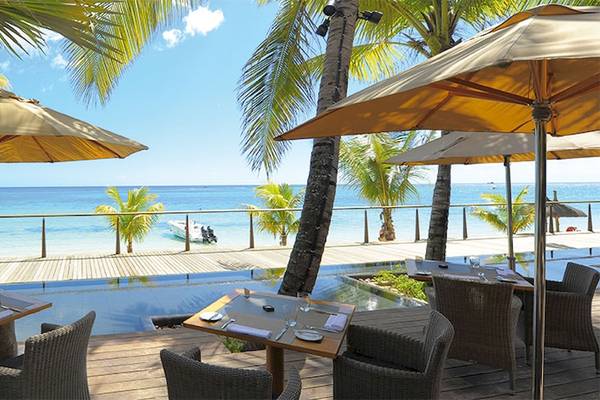 Terrasse des Trou aux Biches Beachcomber Golf Resort & Spa mit Meerblick und Sonnenschirmen.