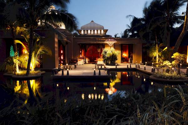 Außenansicht des Trou aux Biches Beachcomber Golf Resort & Spa bei Nacht mit beleuchteten Bäumen und Wasser