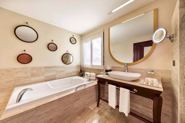Badezimmer im Grand Palladium White Sand Resort & Spa mit Badewanne, Waschbecken und Spiegeln.