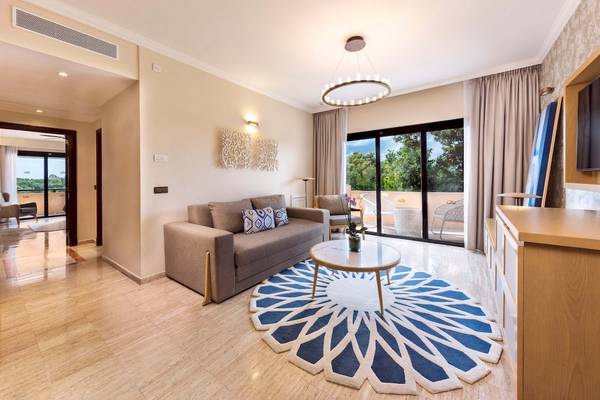 Wohnbereich im Grand Palladium White Sand Resort & Spa mit Sofa, Tisch und Glastür zum Balkon.