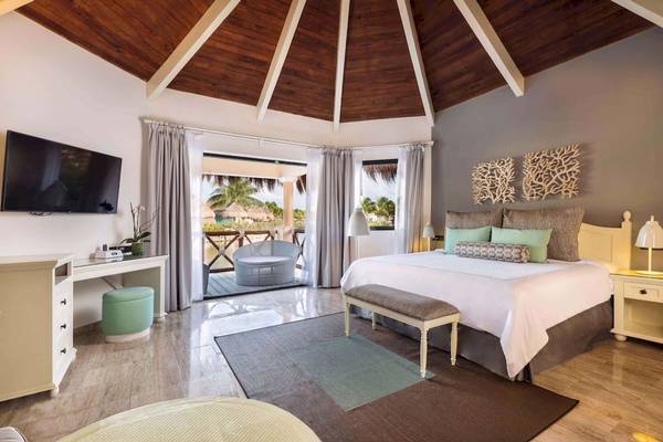 Schlafzimmer im Grand Palladium White Sand Resort mit Bett, Fernseher und Balkon.
