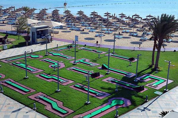 Luftaufnahme des Minigolfplatzes im Pickalbatros White Beach Resort mit Grün, roten Wegen und Strand im Hintergrund.
