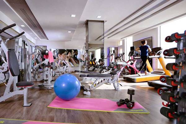 Fitnessstudio im Pickalbatros White Beach Resort mit verschiedenen Geräten und einer Person, die auf einem Laufband läuft.