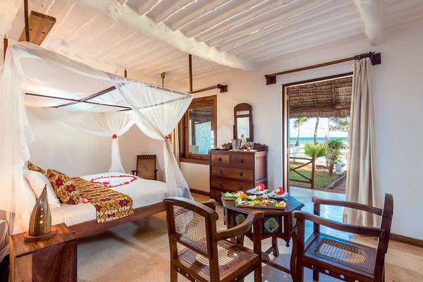 Schlafzimmer im Neptune Pwani Beach Resort mit Bett, Tisch, Stühlen und Meerblick.