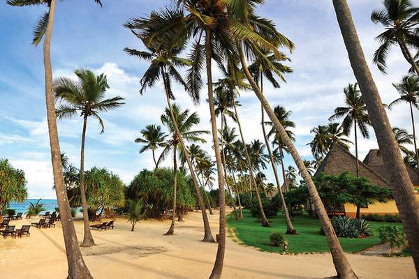 Palmenstrand mit Hotelgebäuden und Sonnenliegen im Neptune Pwani Beach Resort & Spa
