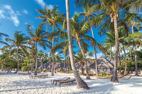 Strand des Neptune Pwani Beach Resorts mit Palmen und Bungalows