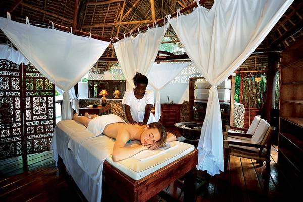 Eine Frau genießt eine Massage in einer Hütte im Neptune Pwani Beach Resort & Spa.