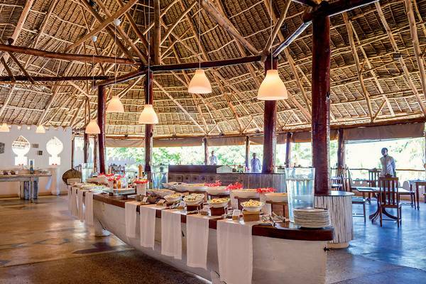 Buffet im Neptune Pwani Beach Resort & Spa mit vielen Speisen und gedeckten Tischen.