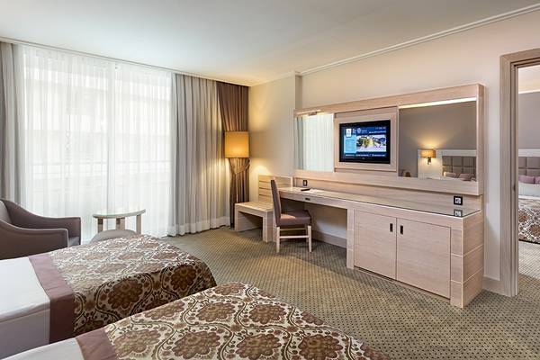 Doppelzimmer im Miracle Resort mit zwei Betten, Schreibtisch, Fernseher und einem Wohnzimmerbereich.