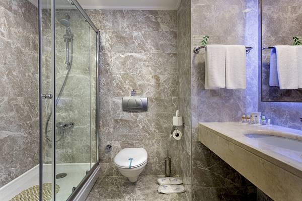 Badezimmer im Miracle Resort mit Marmorfliesen, Dusche, Toilette, Waschbecken und Handtüchern.