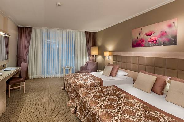 Doppelzimmer im Miracle Resort mit zwei Betten, Schreibtisch, Fernseher, und Blick auf den See.