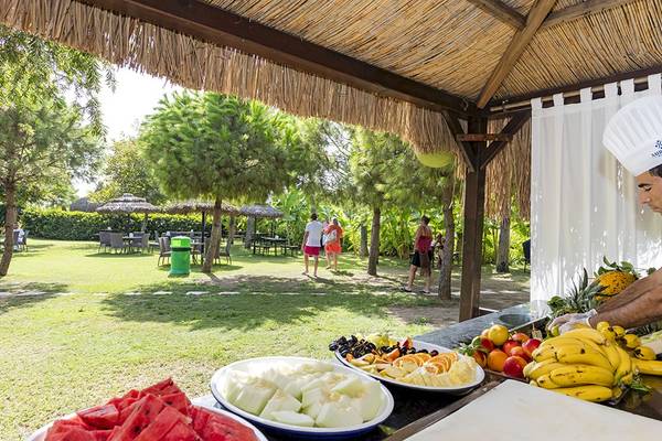 Mann im Miracle Resort, der auf der Terrasse ein Frühstück vorbereitet