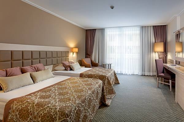 Doppelzimmer im Miracle Resort mit zwei Betten, Schreibtisch, Stühlen und Fernseher.