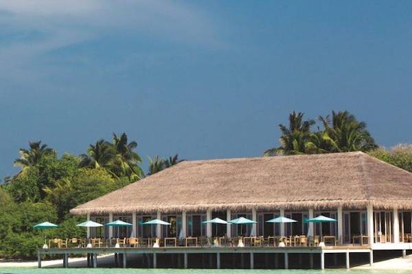 Außenbereich des Oblu Nature Hengeli Resorts mit vielen Tischen und Stühlen unter Sonnenschirmen.