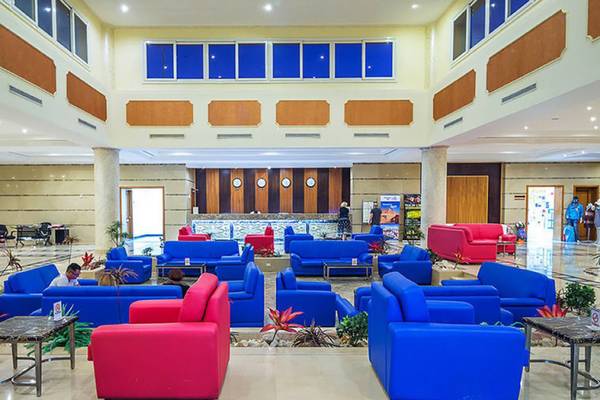 Lobby des Casa Mare Resorts mit blauen und roten Sofas, Empfangstresen und Pflanzen.