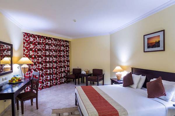 Innenansicht eines Hotelzimmers im Casa Mare Resort mit einem Bett, einem Tisch, Stühlen und einem Spiegel.