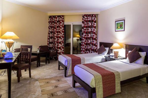 Doppelzimmer im Casa Mare Resort mit zwei Betten, Tisch, Stühlen und Balkon.