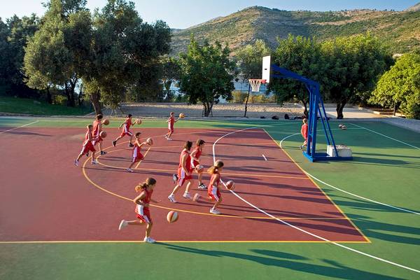 Kinder spielen Basketball auf einem Außenplatz mit einem Basketballkorb.