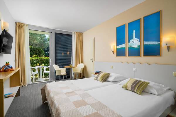 Doppelzimmer im Club Dubrovnik Sunny Hotel mit zwei Betten, Blick auf einen Garten und drei Gemälden an der Wand.
