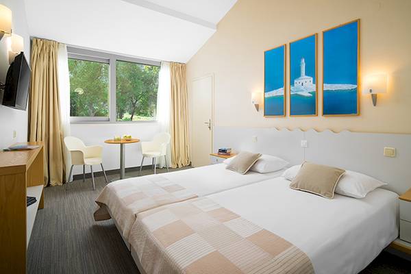 Doppelzimmer im Club Dubrovnik Sunny Hotel mit zwei Betten, Tisch, Stühlen und Fernseher.