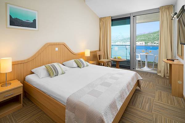 Zimmer im Club Dubrovnik Sunny Hotel mit Blick auf das Meer von einem Balkon.