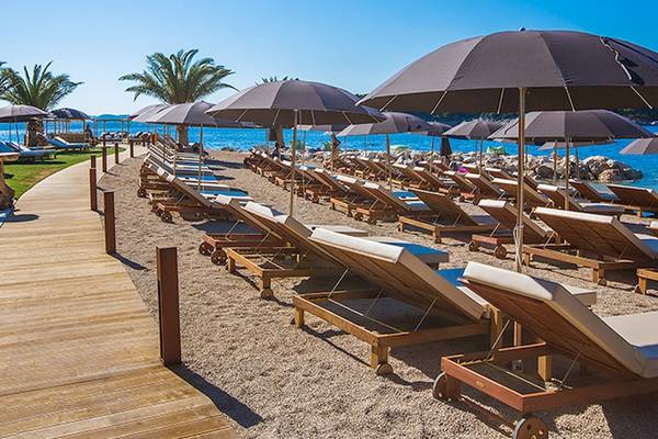 Strand des Club Dubrovnik Sunny Hotel by Valamar mit vielen Sonnenliegen und Schirmen