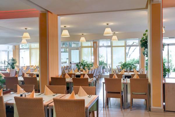 Restaurant im Club Dubrovnik Sunny Hotel by Valamar mit braunen Stühlen und Tischen.