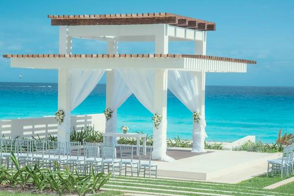 Strandzeremonie am Coral Level im Iberostar Selection Cancun mit weißem Pavillon und Blick auf das Meer.