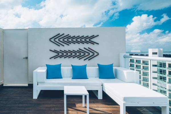 Balkonbereich des Coral Level at Iberostar Selection Cancun mit weißem Sofa, blauen Kissen und Tisch