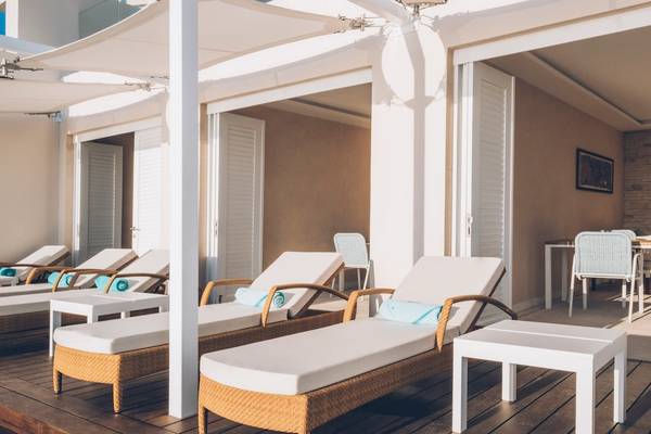 Loungebereich im Coral Level at Iberostar Selection Cancun mit weißen Liegestühlen und Tischen.
