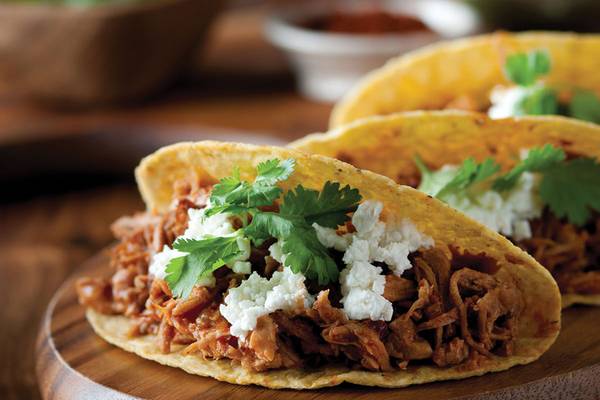 Ein Taco mit Rinderfleisch und Feta auf einer Holzplatte.
