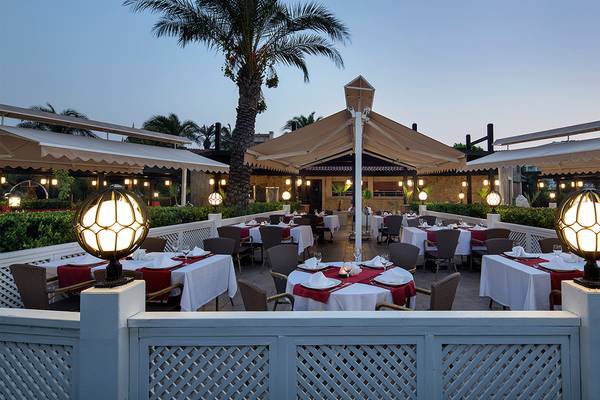 Alfresco-Essbereich im Crystal Family Resort & Spa mit Tischen und Stühlen unter einer Markise.