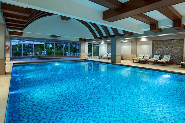 Innenpool im Crystal Family Resort & Spa mit Lounge-Liegestühlen und Glaswänden.