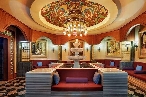 Loungebereich im Crystal Family Resort & Spa mit zentralem Brunnen, roten Sitzgelegenheiten und dekorativen Wandgemälden.
