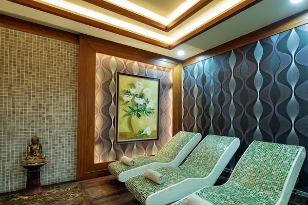 Massageraum im Kristall Family Resort & Spa mit drei Liegen und einer Buddha-Statue.
