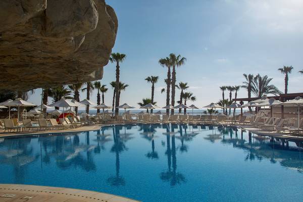 Poolbereich des Louis Althea Beach Hotels mit Sonnenliegen und Palmen