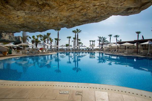 Pool im Louis Althea Beach Hotel mit Liegestühlen und Sonnenschirmen.