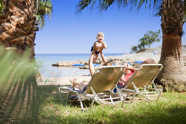 Familie im Louis Althea Beach Hotel am Strand mit einem Baby, das hochgehoben wird