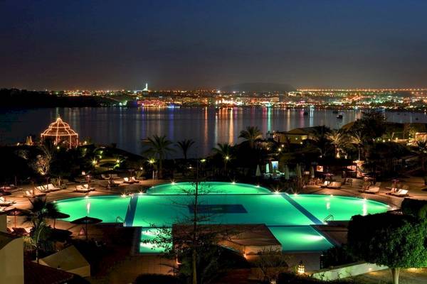 Nachtansicht des Moevenpick Resort Sharm el Sheikh mit beleuchtetem Pool und Stadt im Hintergrund