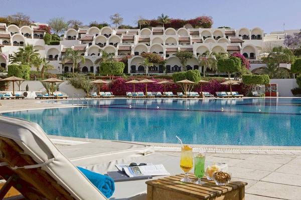 Poolbereich des Movenpick Resort Sharm el Sheikh mit Sonnenliegen und Getränken.