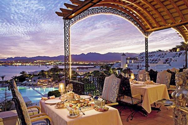 Aussichtsterrasse im Mövenpick Resort Sharm el Sheikh mit Tischen und Blick auf den Pool und die Stadt